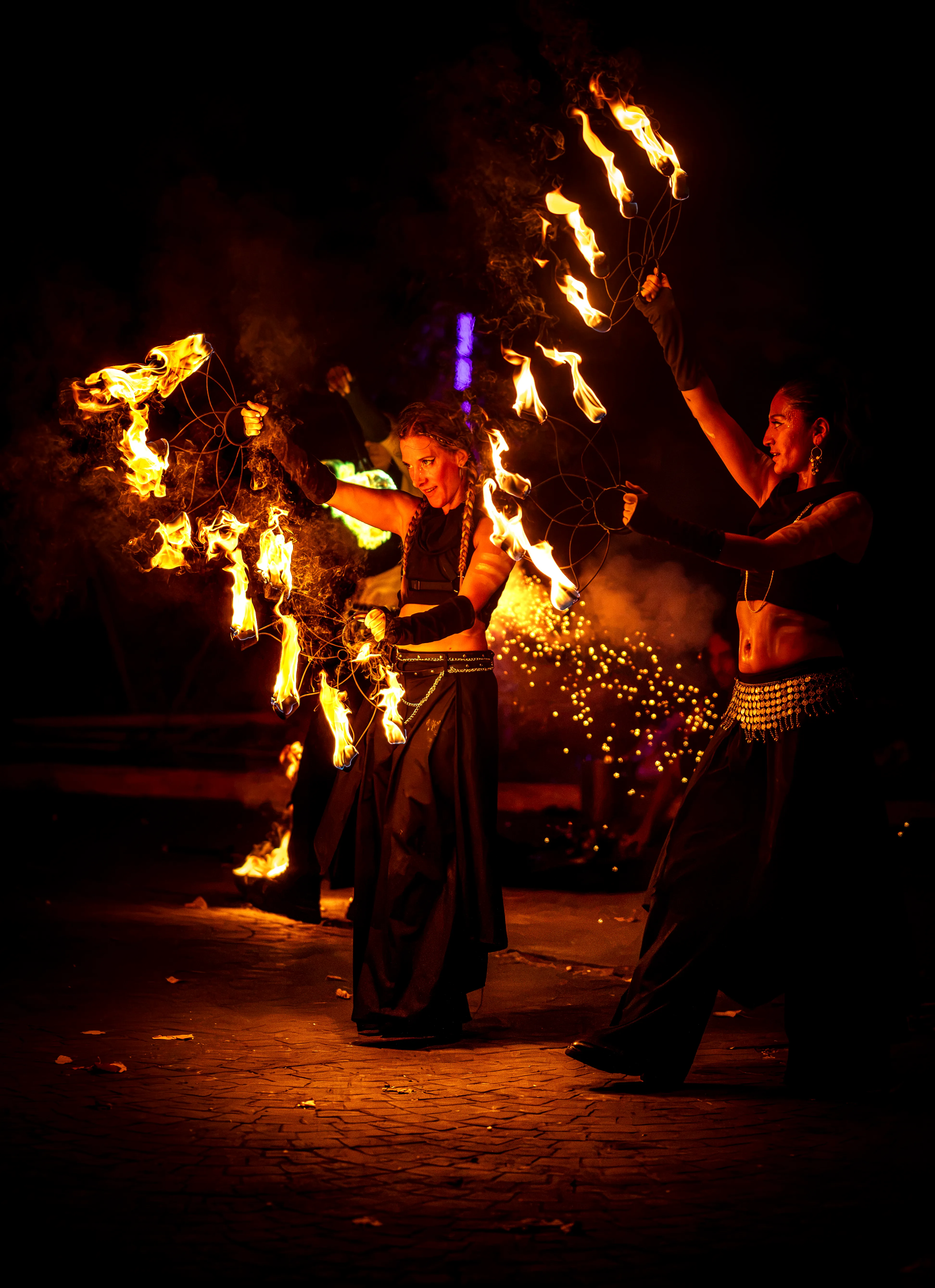 Two performers with fire fans at night